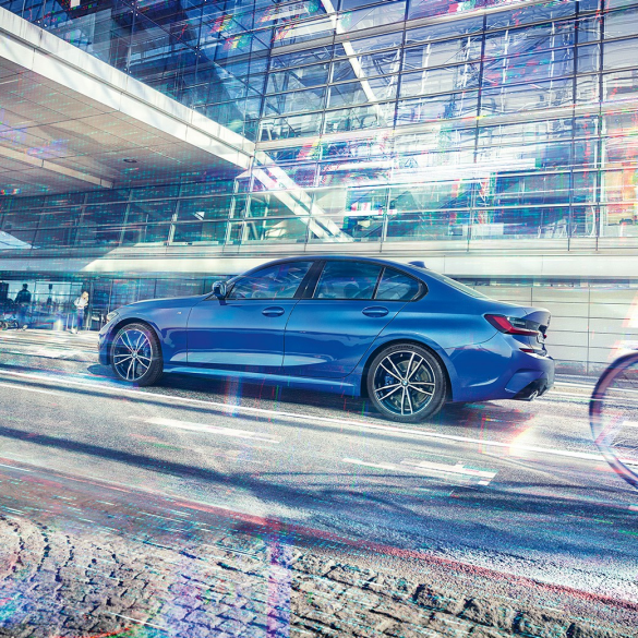 BMW 3 Series Sedan, side view. Still shot of the BMW 3 Series Sedan from the side on the day in front of a glass building.