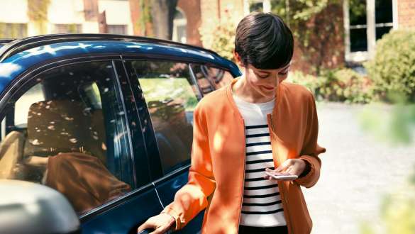 Woman looking at smartphone Woman getting out of BMW looking at smartphone