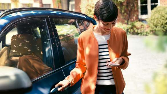 BMW Teleservices BMW Teleservices woman with smartphone next to the door of her BMW