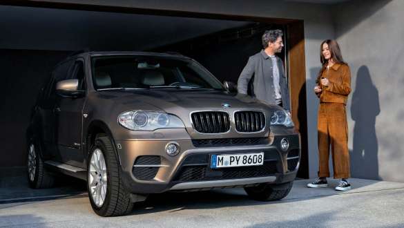 BMW Value Service man and woman in front of garage with BMW X5 BMW Value Service man and woman in front of garage with BMW X5