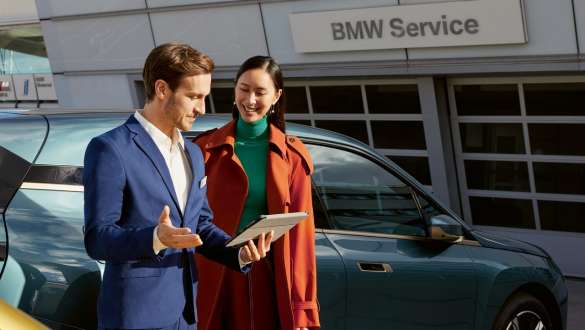 BMW Service Woman and man talking in front of BMW iX BMW Service Woman and man talking in front of BMW iX