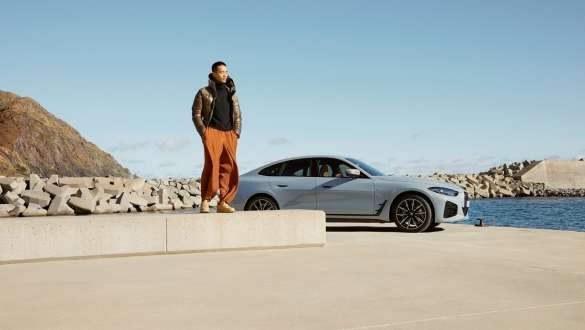 BMW Service Inclusive BMW Service Inclusive Man standing on stony elevation in front of a BMW vehicle with water in the background