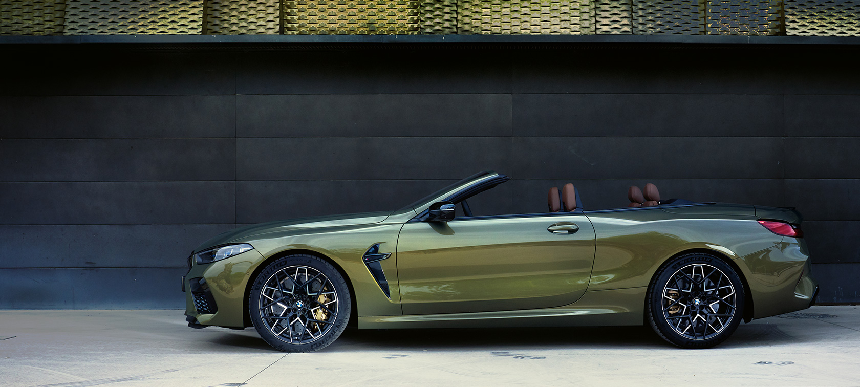 BMW M8 Competition Convertible F91 LCI Facelift 2022 side view standing BMW M8 Competition Convertible F91 LCI Facelift 2022 BMW Individual Brass metallic side view standing with open door and female model