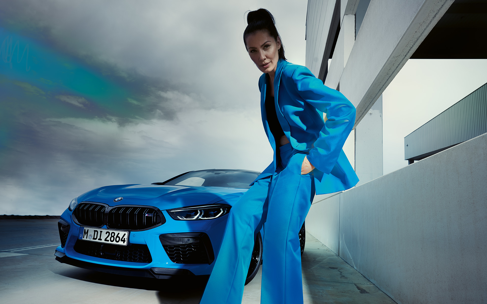 BMW M8 Competition Coupé F92 LCI 2022 three-quarter front view BMW M8 Competition Coupé F92 LCI Facelift 2022 Daytona Beach blue uni three-quarter front view with a female model in blue trouser suit