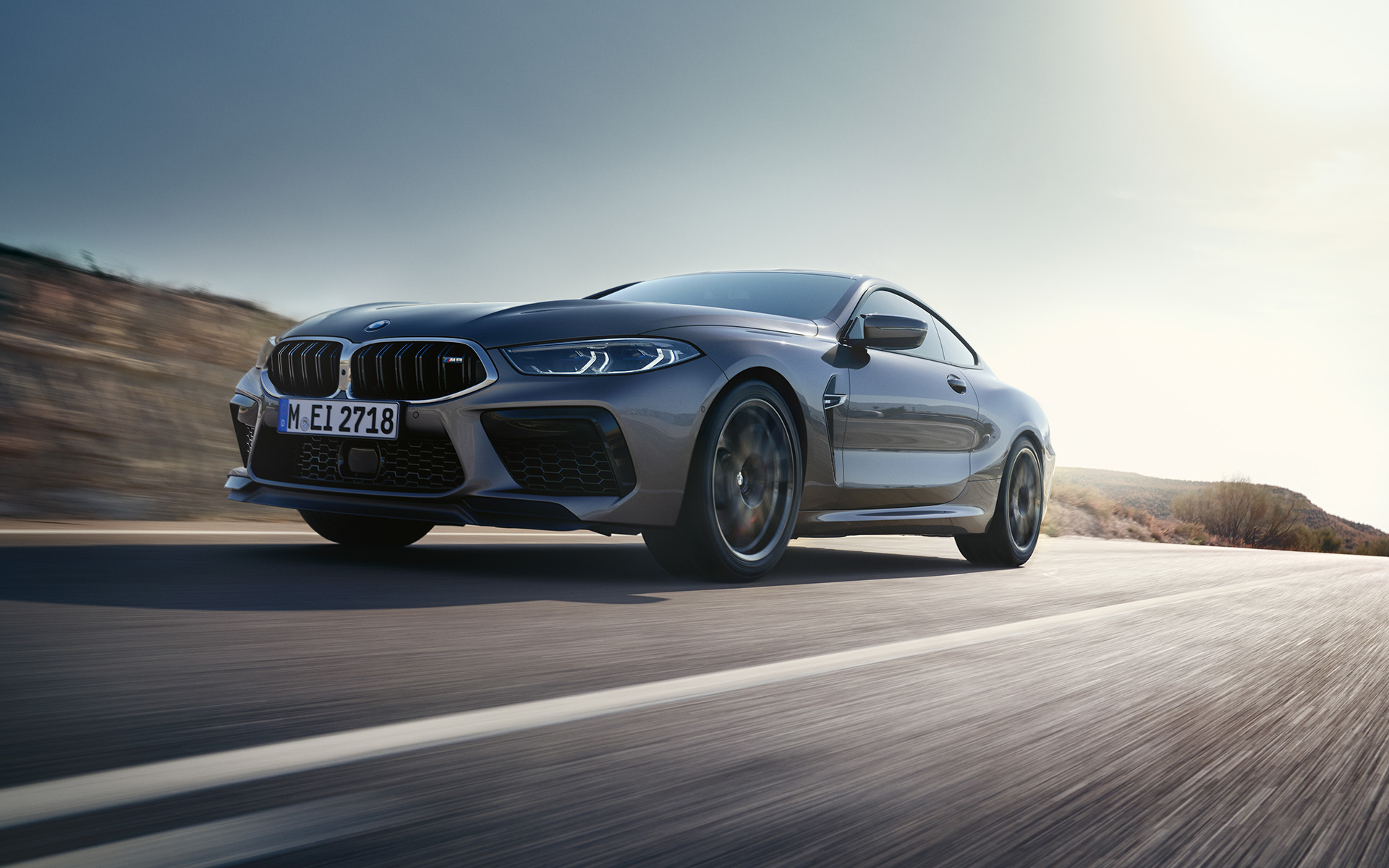 Three-quarter front view BMW M8 Coupé F92 LCI Facelift 2022 driving on a highway BMW M8 Coupé F92 LCI Facelift 2022 Skyscraper grey metallic three-quarter front view driving on a highway low angle shot