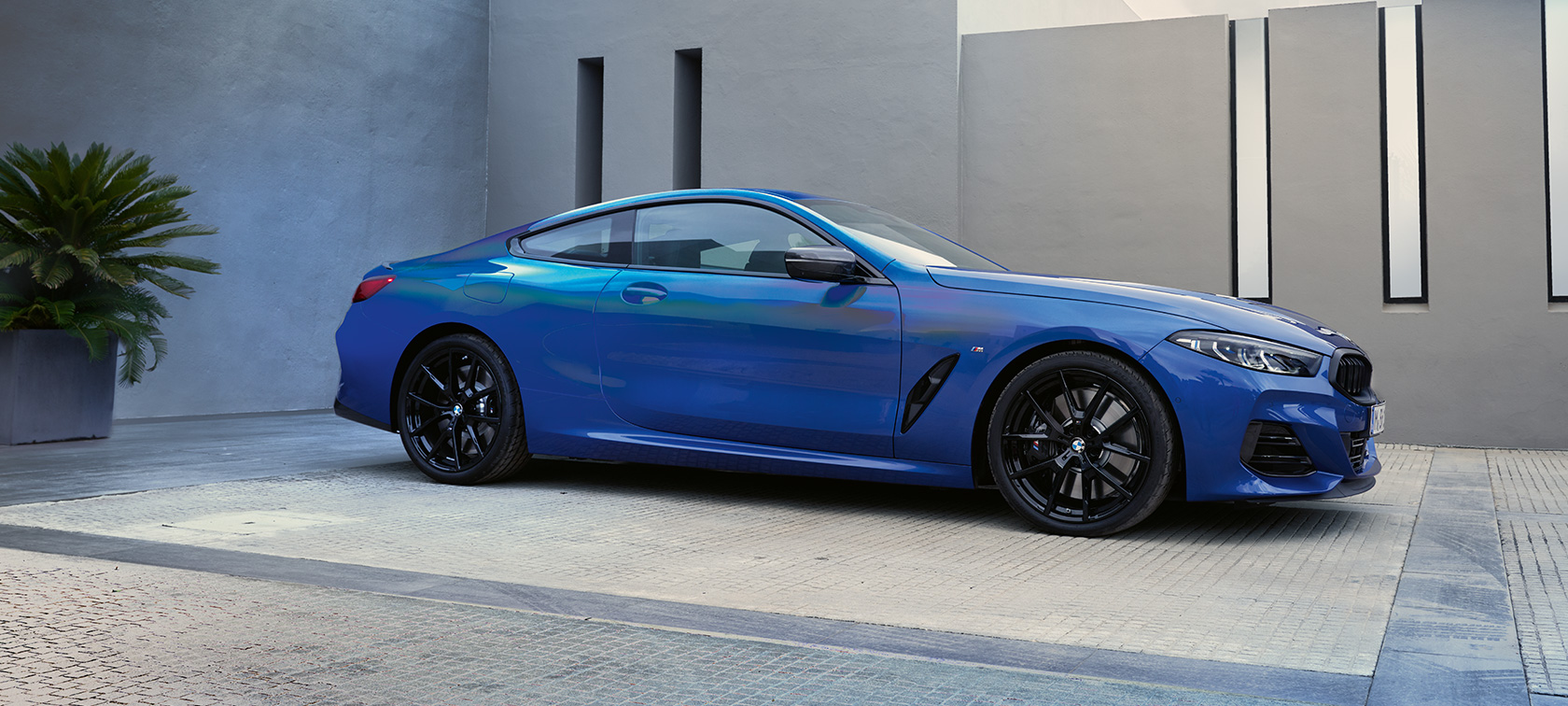 Side view BMW M850i xDrive Coupé G15 LCI Facelift 2022 BMW M850i xDrive Coupé G15 LCI Facelift 2022 M Portimao Blue metallic side view standing in front of a building