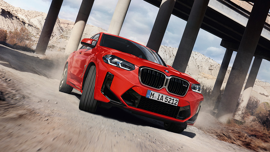BMW X4 M F98 LCI Facelift 2021 Toronto Red metallic three-quarter front view in front of bridge columns