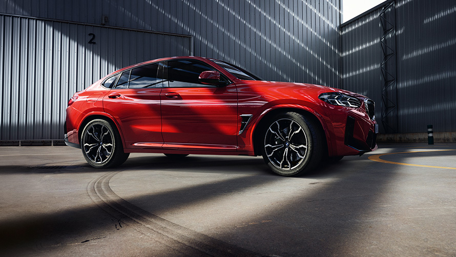 BMW X4 M F98 LCI Facelift 2021 Toronto Red metallic side view in front of factory building