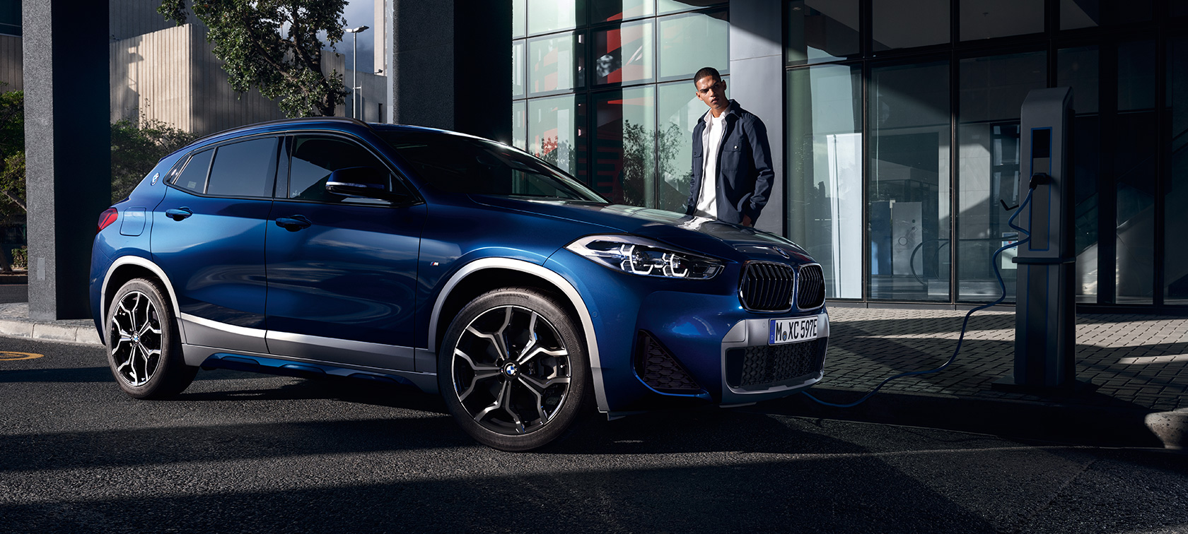 Plug-in hybrid BMW X2 xDrive25e F39 three-quarter side view on charging station Plug-in hybrid BMW X2 xDrive25e F39 three-quarter side view on charging station with model