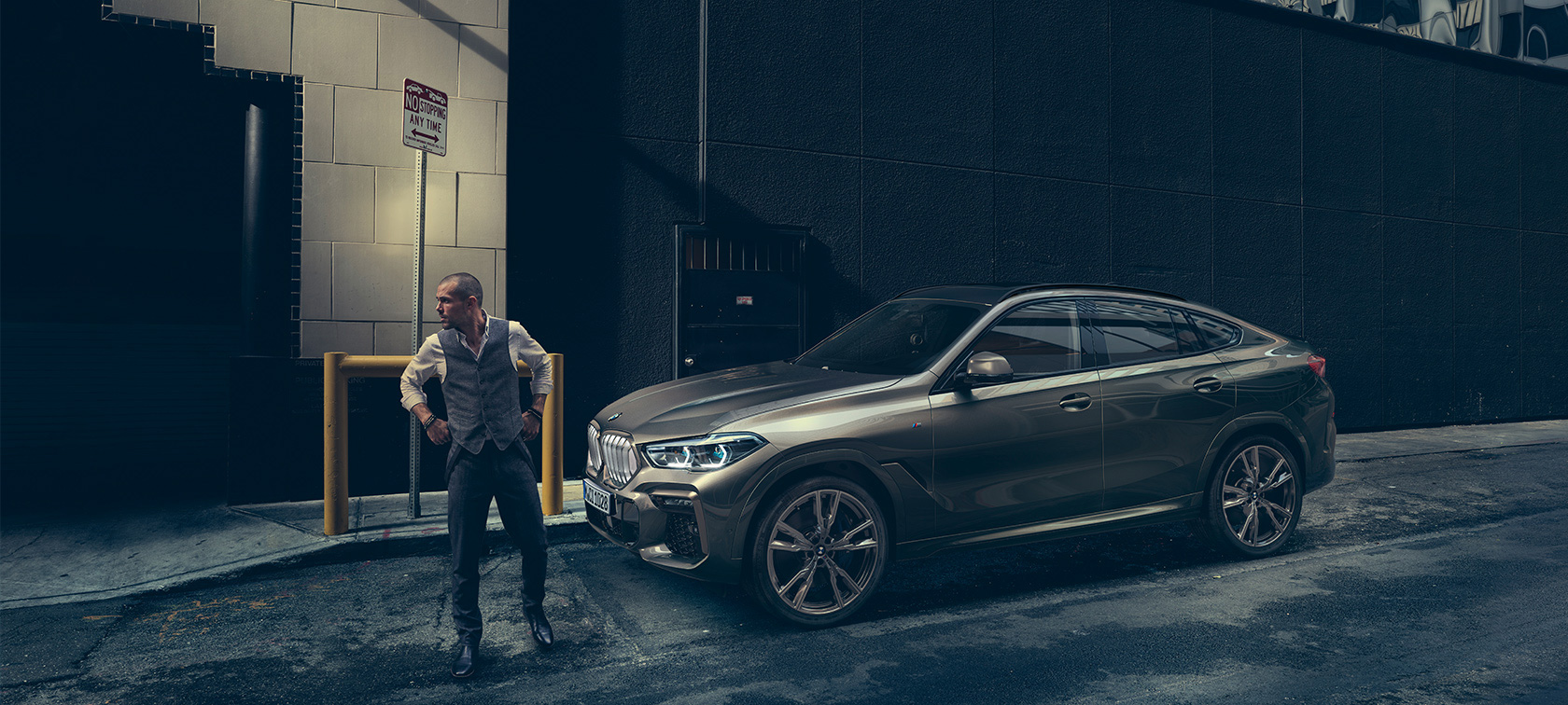 BMW X6 in lateral perspective in front of an urban setting.