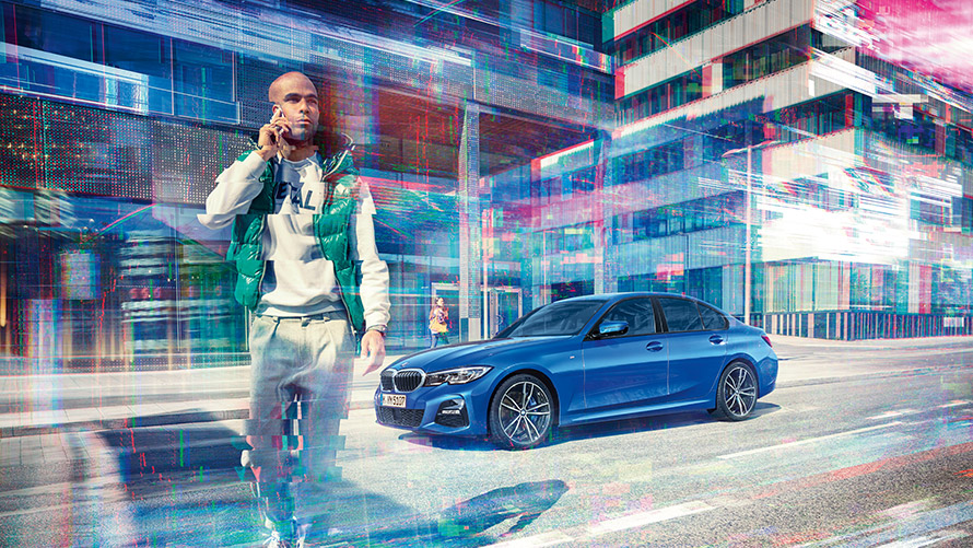 Blue BMW with phoning man Man phones, in the background a blue BMW in front of urban setting