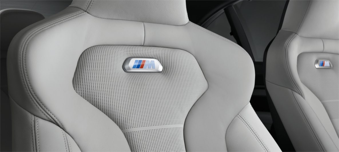 BMW M Interior – High-Performance Sport Seats with Motorsport-Inspired Craftsmanship Close-up of BMW M performance sport seats in light grey leather with M logo badge, showcasing premium motorsport-inspired design