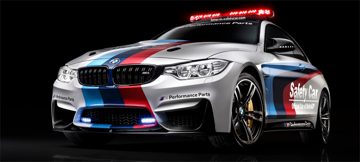 BMW M4 Coupé MotoGP Safety Car with M Performance Parts and tri-color livery under studio lighting, emphasizing motorsport partnership and innovation