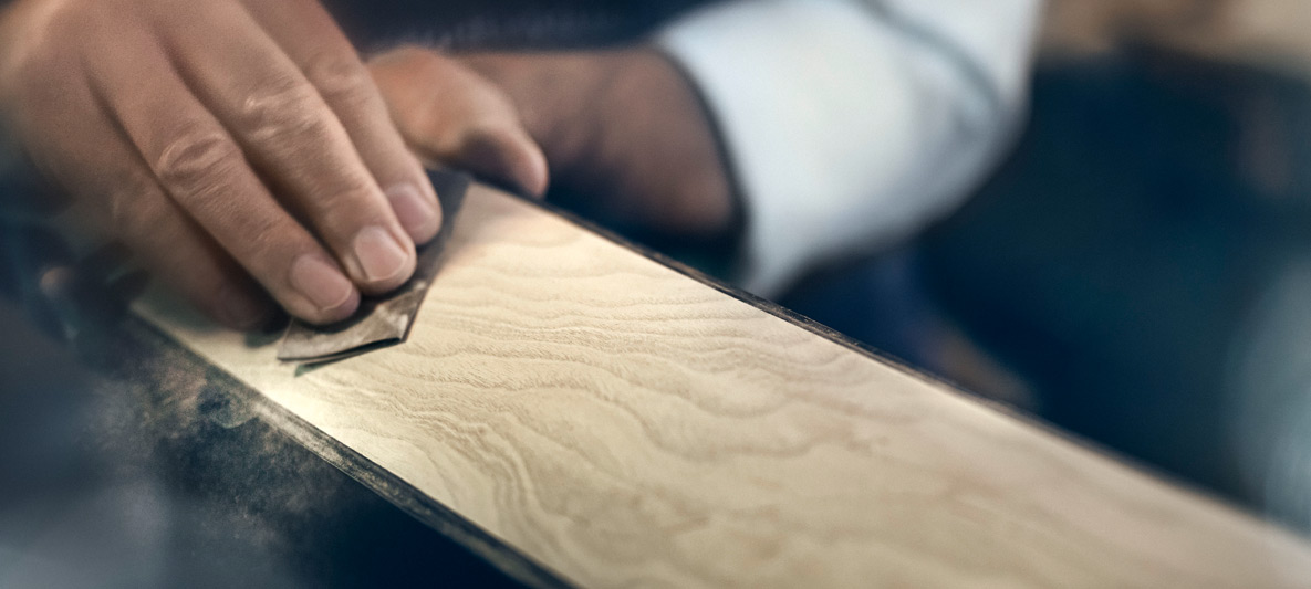 Craftsman hand-finishing a luxury wood trim piece for a BMW Individual vehicle, highlighting bespoke craftsmanship and personalized design