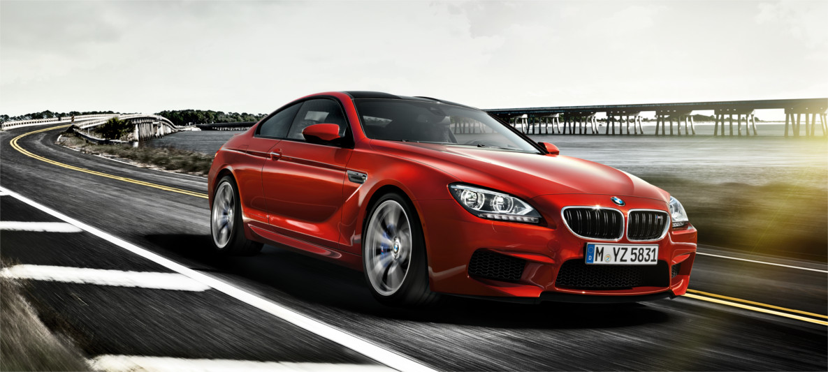 BMW M6 Coupé – High-Performance Gran Tourer with M Power and Precision Red BMW M6 Coupé driving on a coastal road at speed, emphasizing luxury performance, agility, and signature M styling
